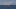 A red fishing boat cruises on the sea. with a background of snowy mountains