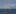 A red fishing boat cruises on the sea. with a background of snowy mountains